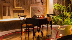 Une ambiance romantique pour un dîner, avec une table dressée pour deux, entourée de boiseries et agrémentée d’un mur décoratif.