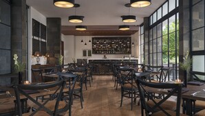 Ein Restaurant mit Holzboden, schwarzen Stühlen und Pendelleuchten.