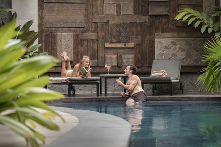 Una piscina al aire libre, sillones reclinables de piscina