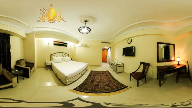 Una habitación de hotel con cama, escritorio, silla, televisión y baño.