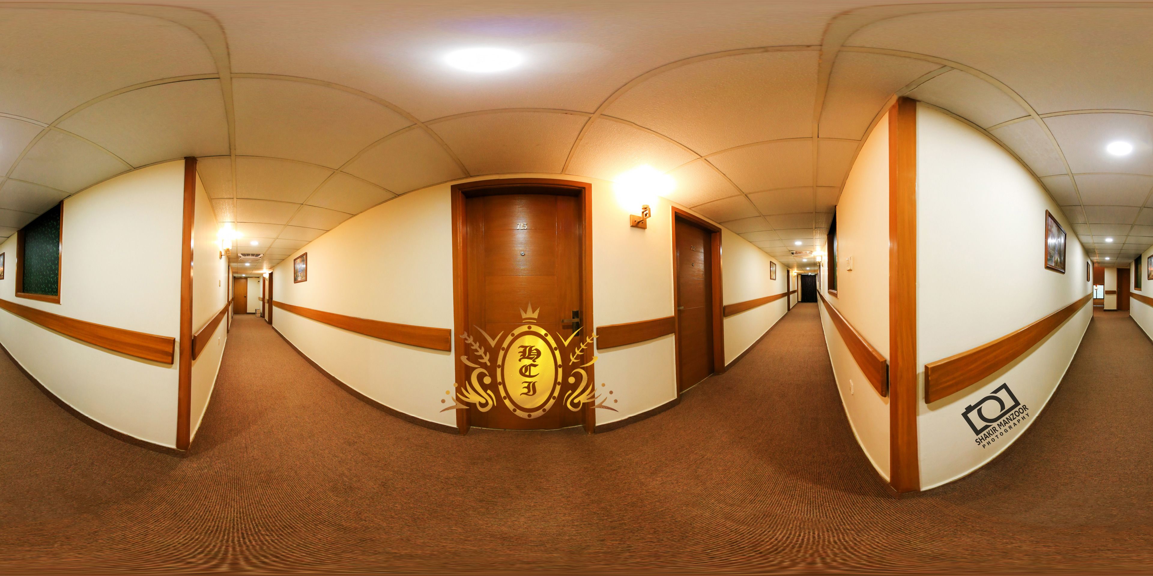 A long, curved hallway with wooden doors and a carpeted floor.