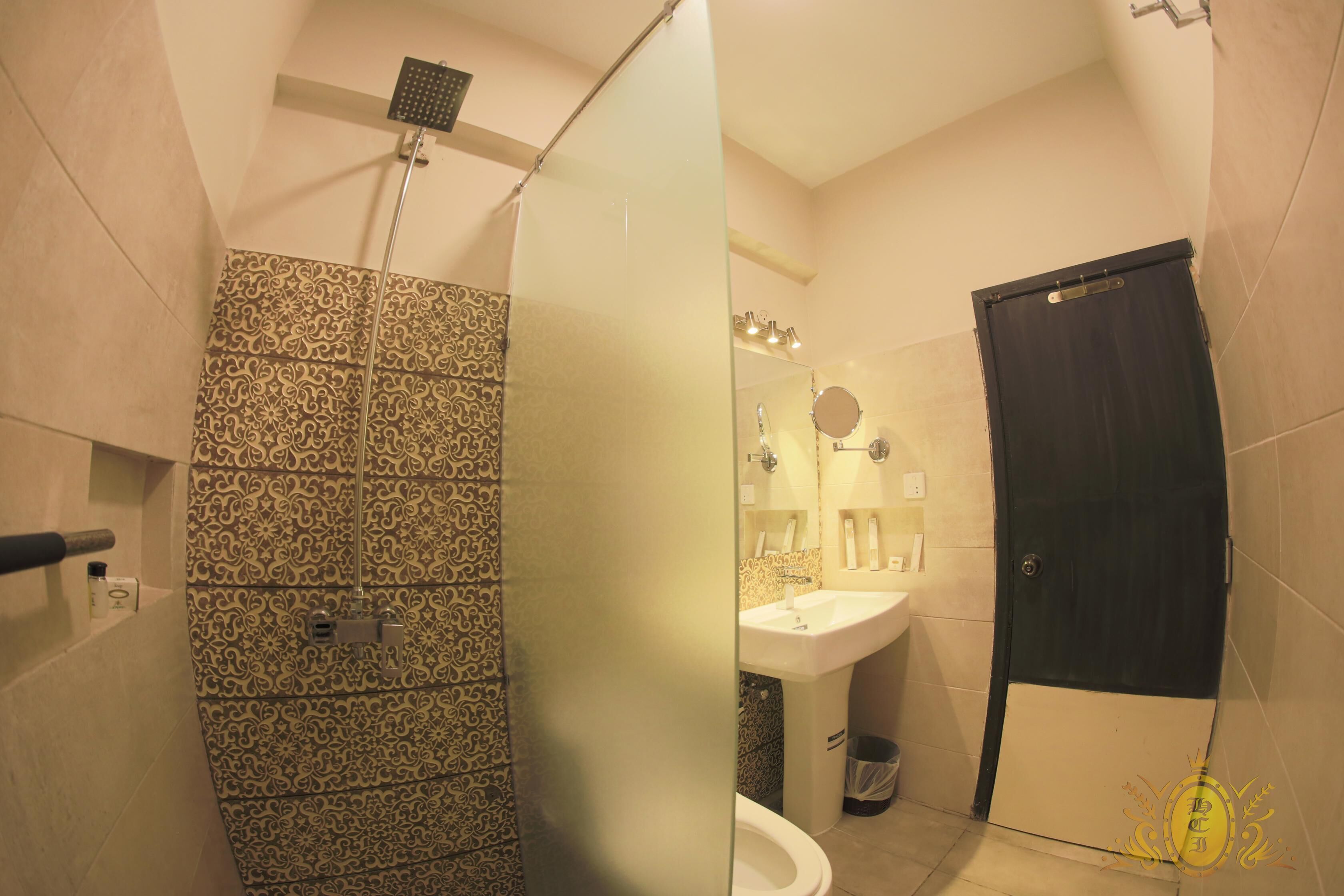 Um banheiro com azulejos estampados, chuveiro, pia e vaso sanitário.