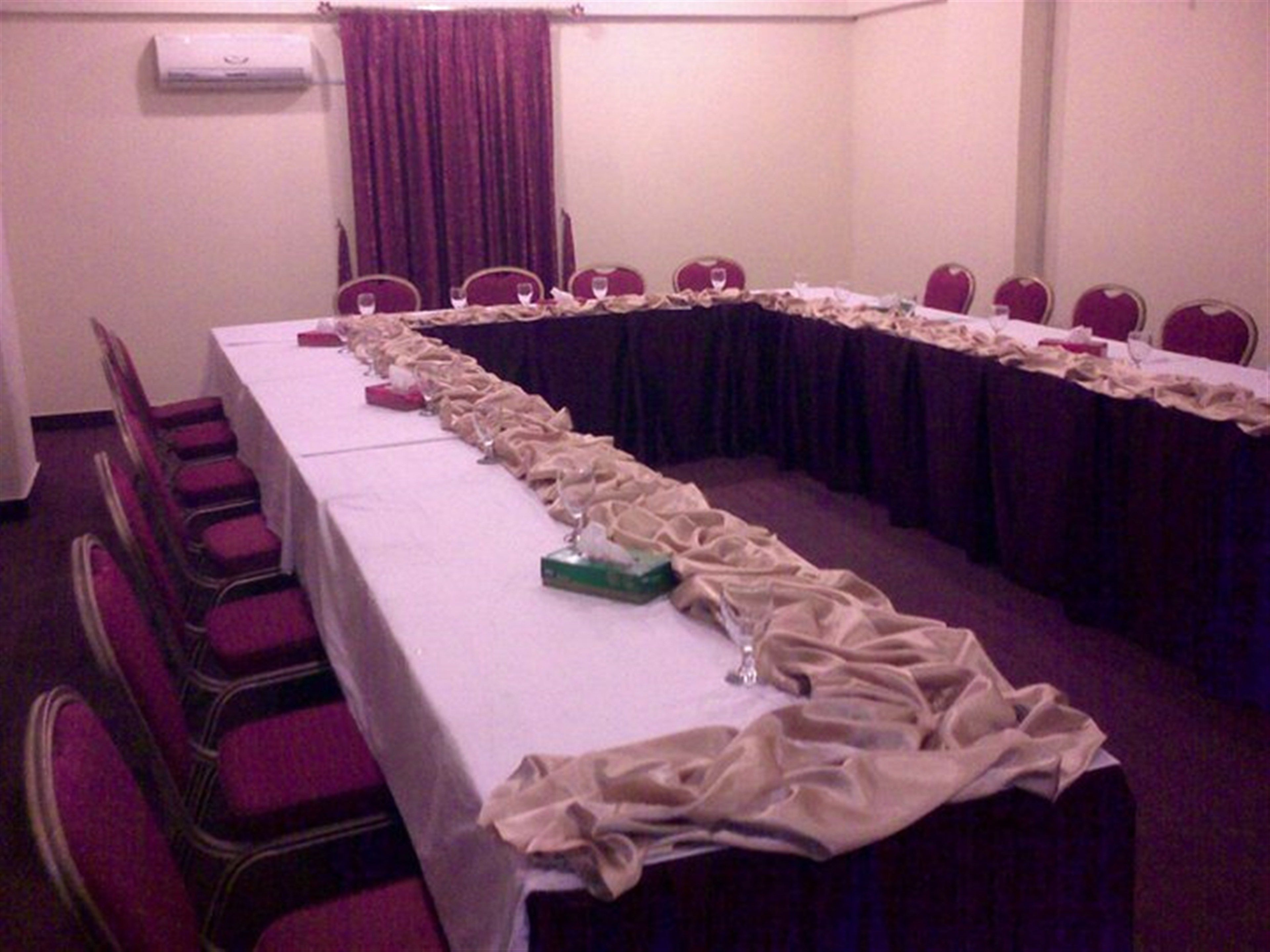 A conference room with a long table, chairs, and a curtain.