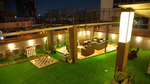 Terraza en la azotea con césped artificial, mobiliario exterior y plantas en macetas.