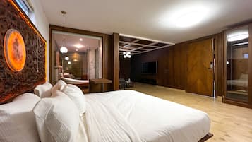 A modern bedroom with a large bed, a TV, and a wooden floor.