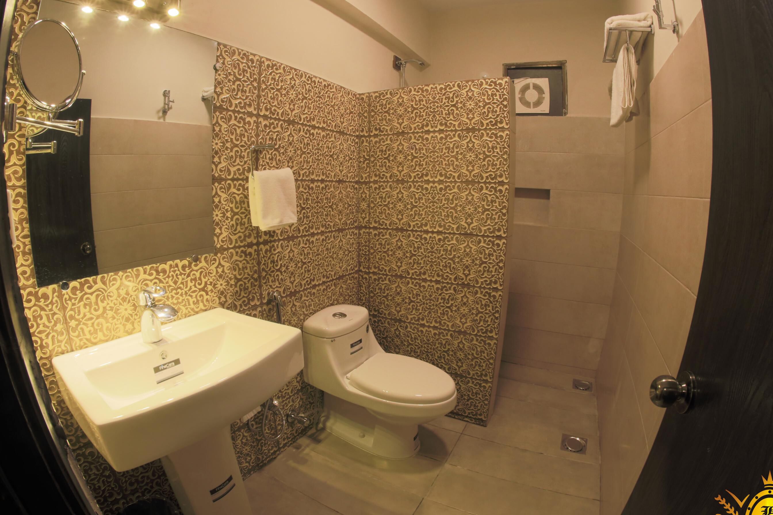 A bathroom with a sink, toilet, and patterned tiles.