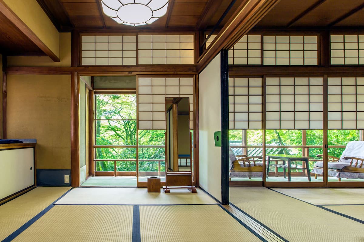 A traditional Japanese room with tatami flooring, sliding doors, and a view of a garden.