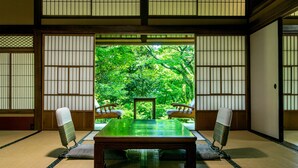 Um quarto japonês tradicional com tatames, uma mesa baixa e duas cadeiras.