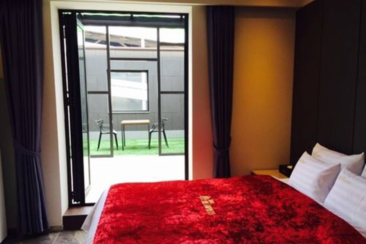 Habitación de hotel con una cama grande, vistas a un patio interior y una puerta corredera que da al exterior.