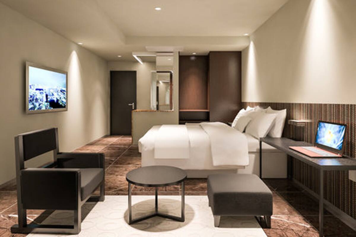 Una habitación de hotel moderna con cama, mesita de noche, silla y televisión.