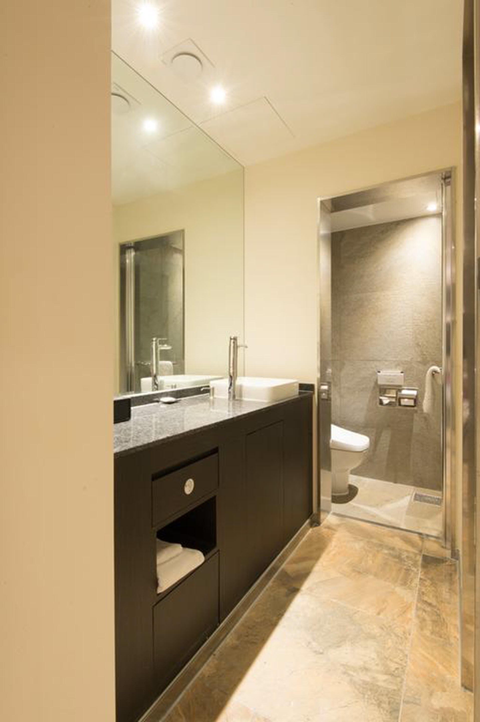 A modern bathroom with a large mirror, a sink, and a shower area.