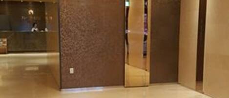 A spacious lobby with a polished floor and a mirrored wall.