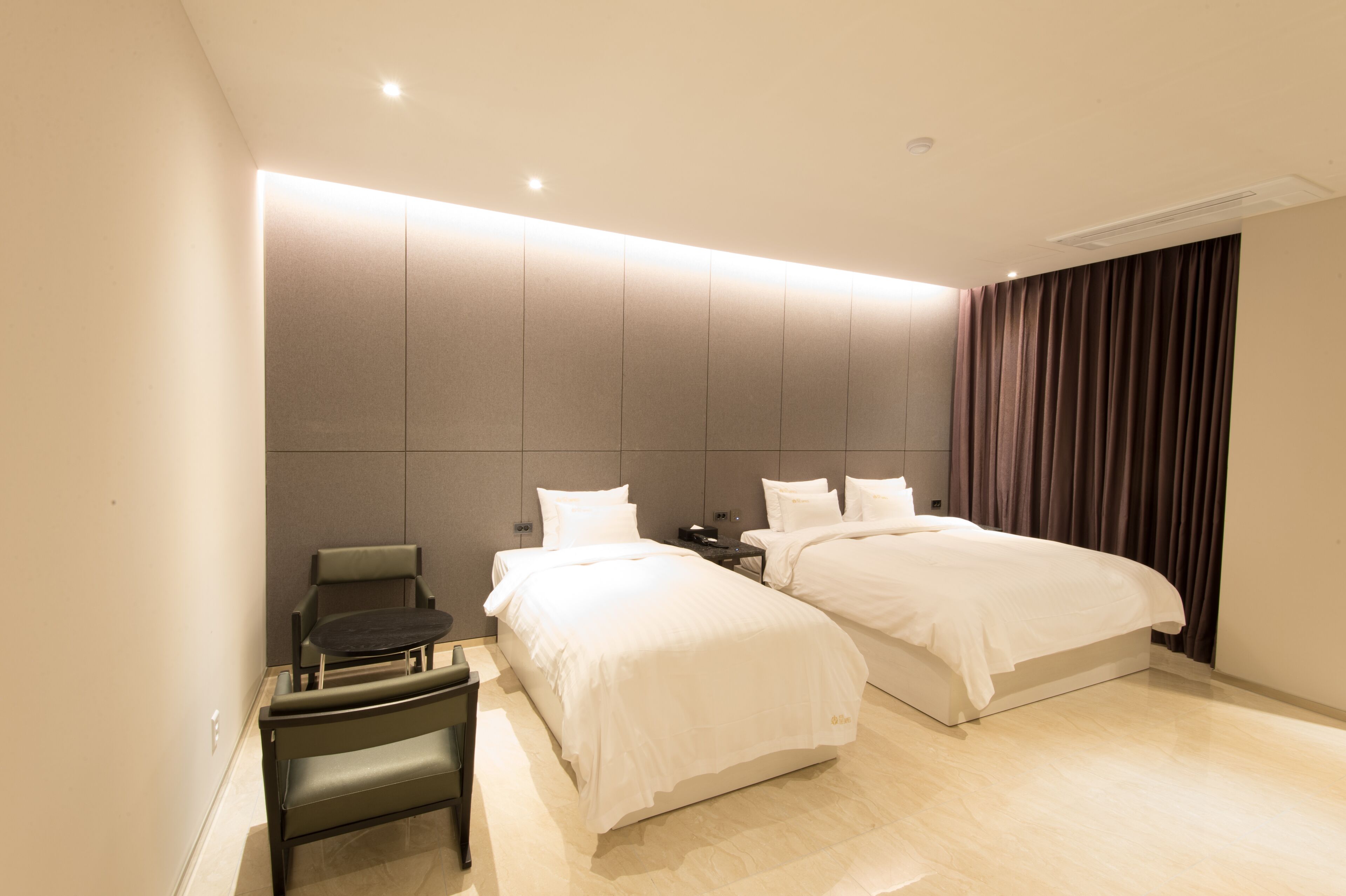 A hotel room with two beds, a desk, and a chair.