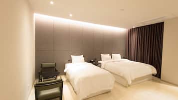 A hotel room with two beds, a desk, and a chair.
