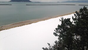 A beach with a clear view of the ocean, a distant mountain, and a pier.