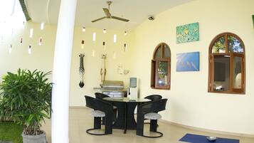 A dining area with a table and chairs, a ceiling fan, and a potted plant.