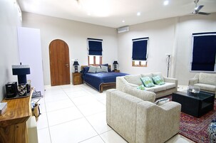 A well-lit bedroom with a bed, two sofas, a coffee table, and a desk with a computer.