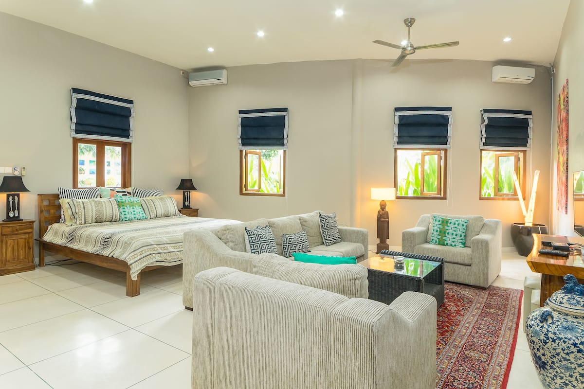 A spacious living room with a large bed, two sofas, a coffee table, and a TV.