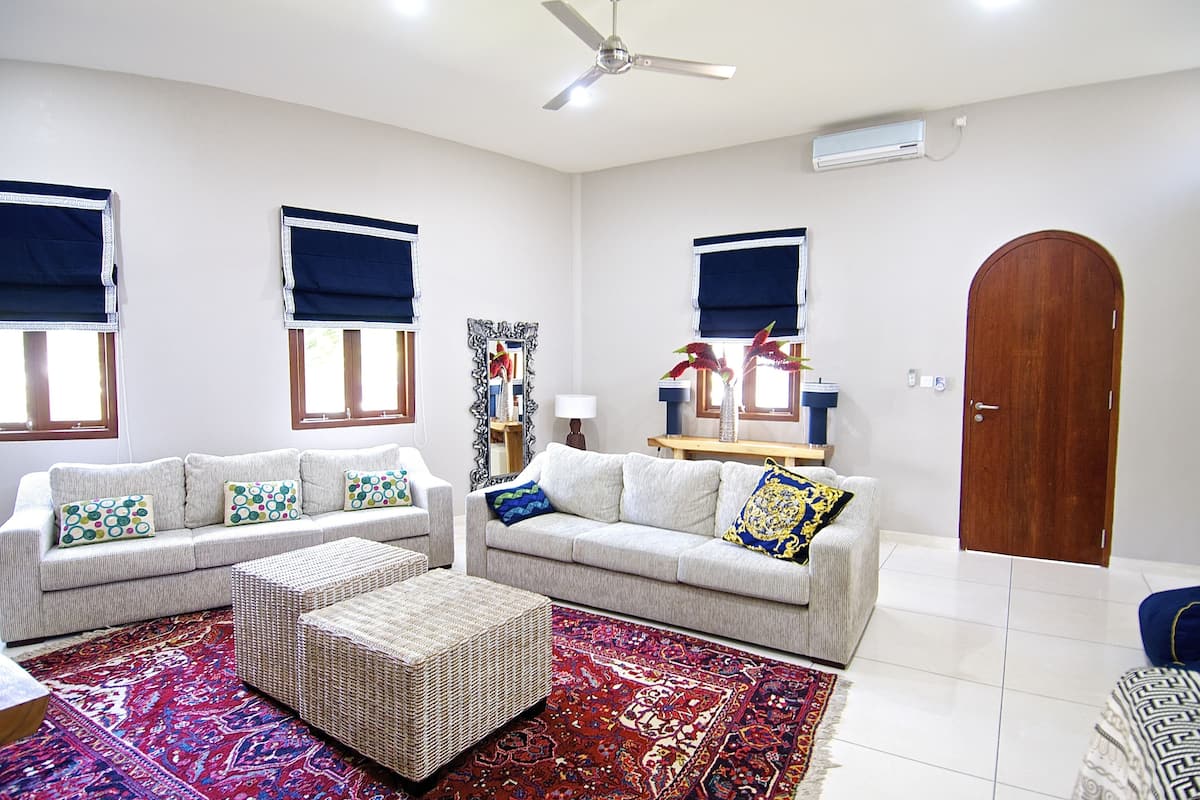 A living room with two sofas, a coffee table, a patterned rug, and a wooden door.