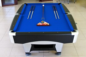 A pool table with a blue felt surface, surrounded by four pool cues, a cue ball, and a triangular rack of billiard balls.