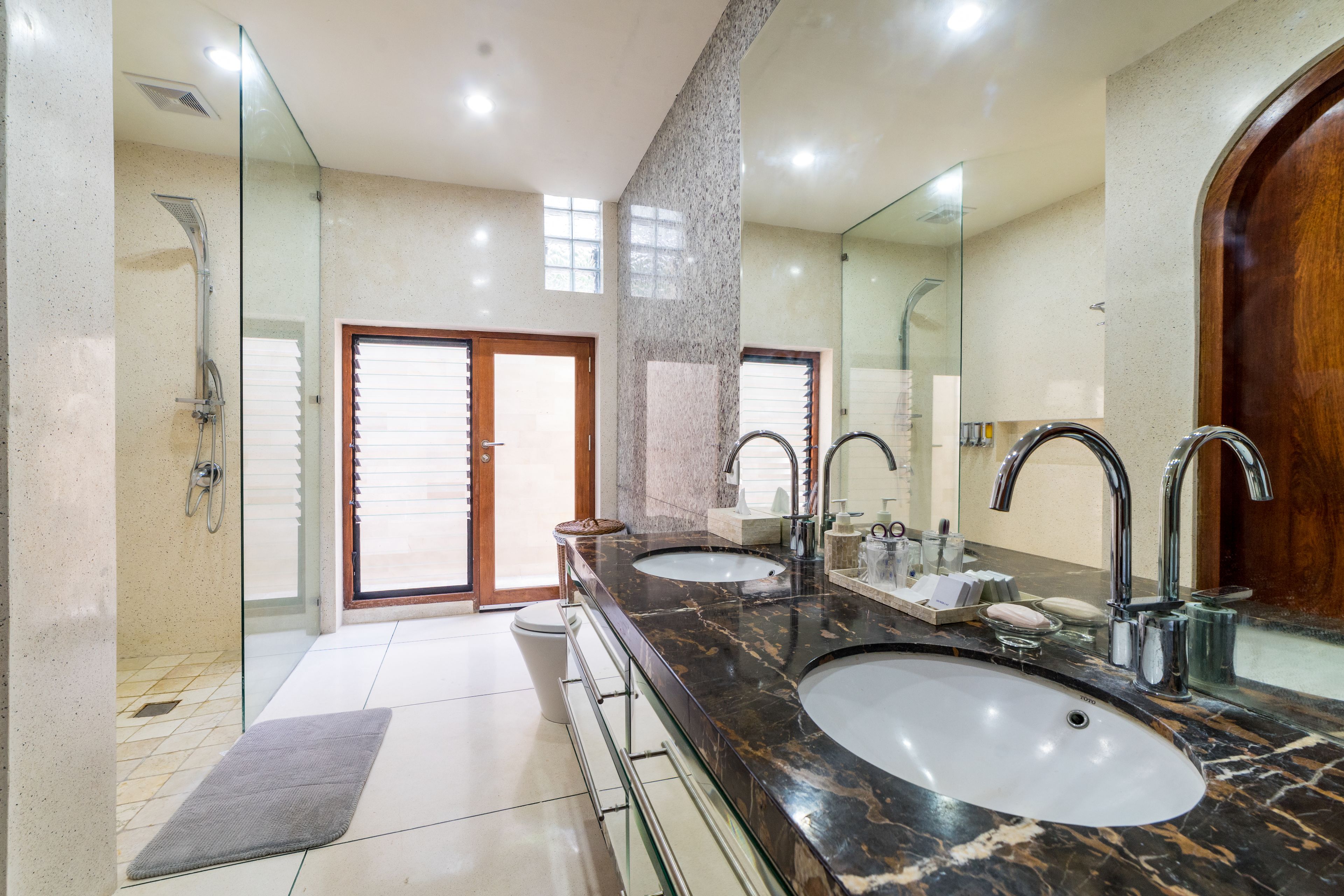 A modern bathroom with two sinks, a shower, and a large mirror.