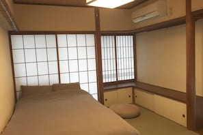 A traditional Japanese-style room with tatami flooring, a low bed, sliding shoji doors, and a small tatami mat in the corner. - Belle Via Tokyo (Tokyo)