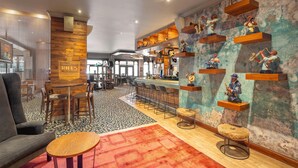 A bar area with a bar counter, stools, and a seating area with a sofa and round table. - Garden Court Sandton City (Sandton)