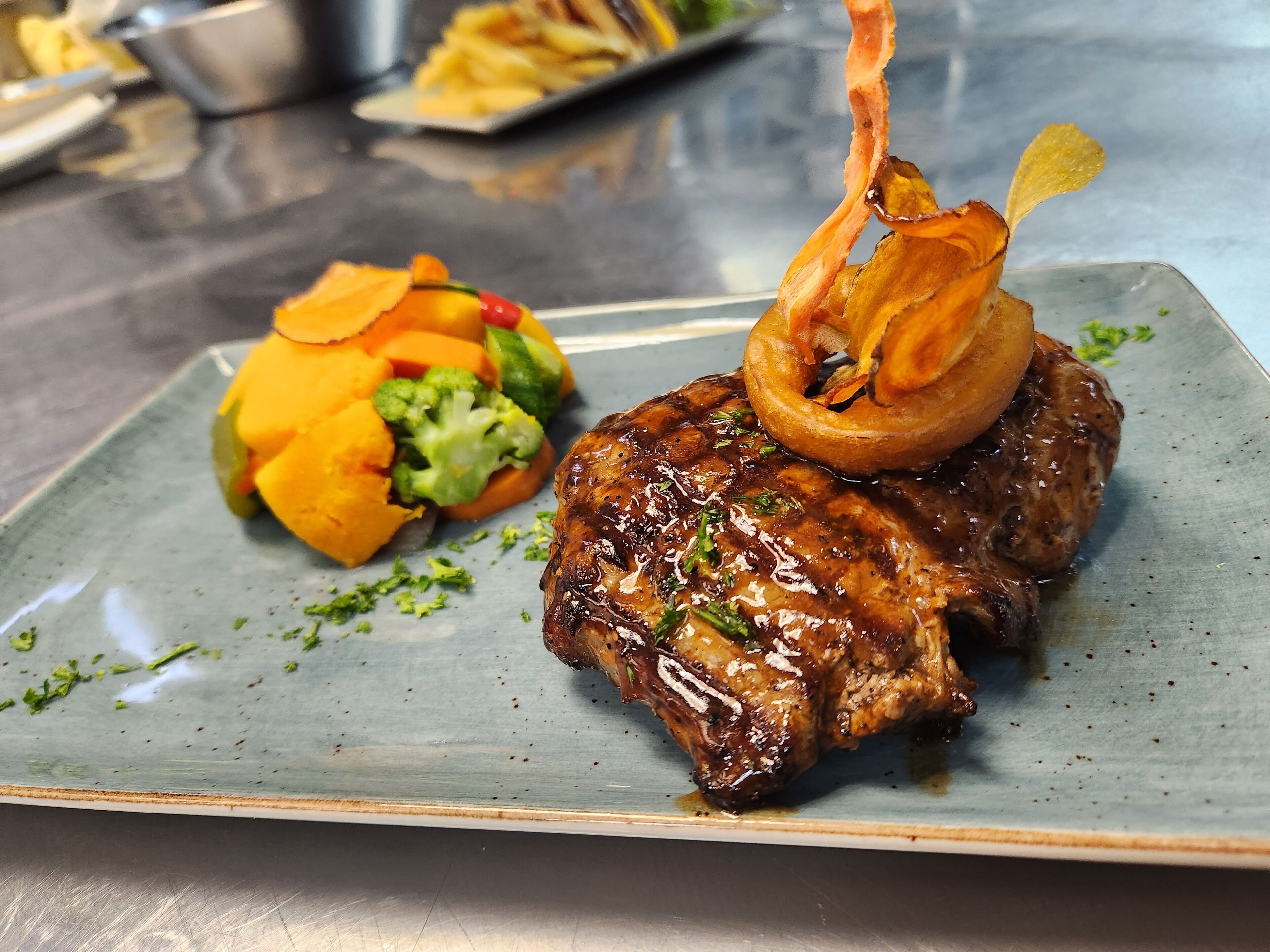 Un plato con un bistec, verduras a la parrilla y una guarnición.