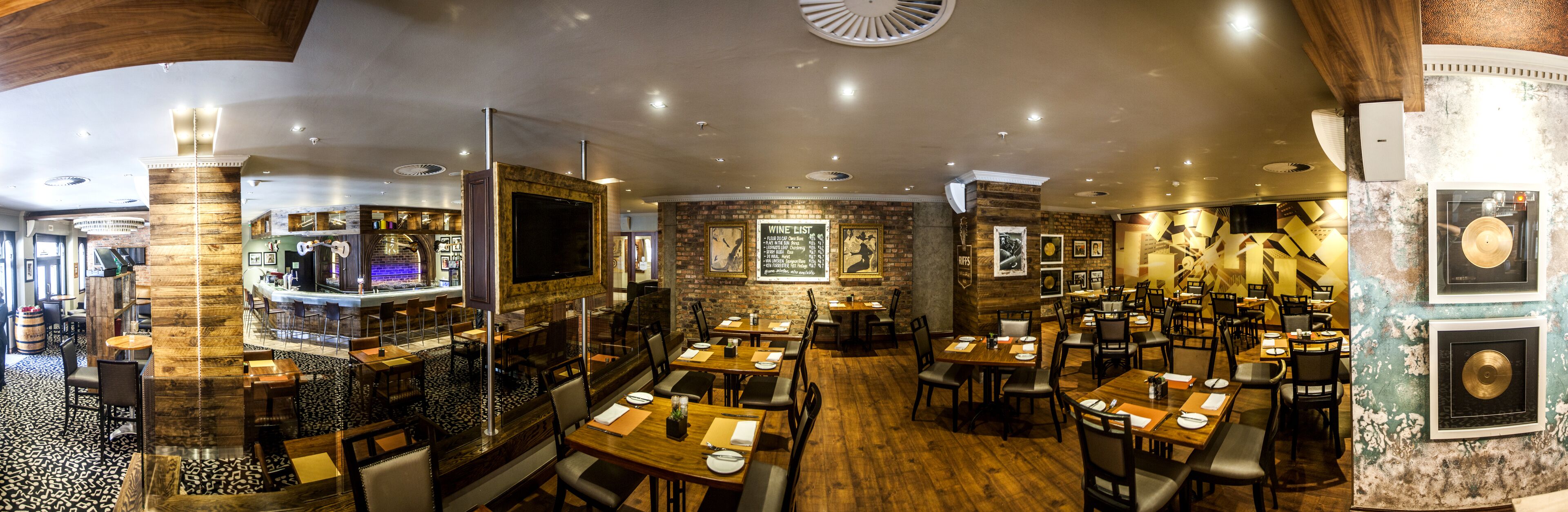 A restaurant with a bar area, multiple dining tables, and a stage for live performances.
