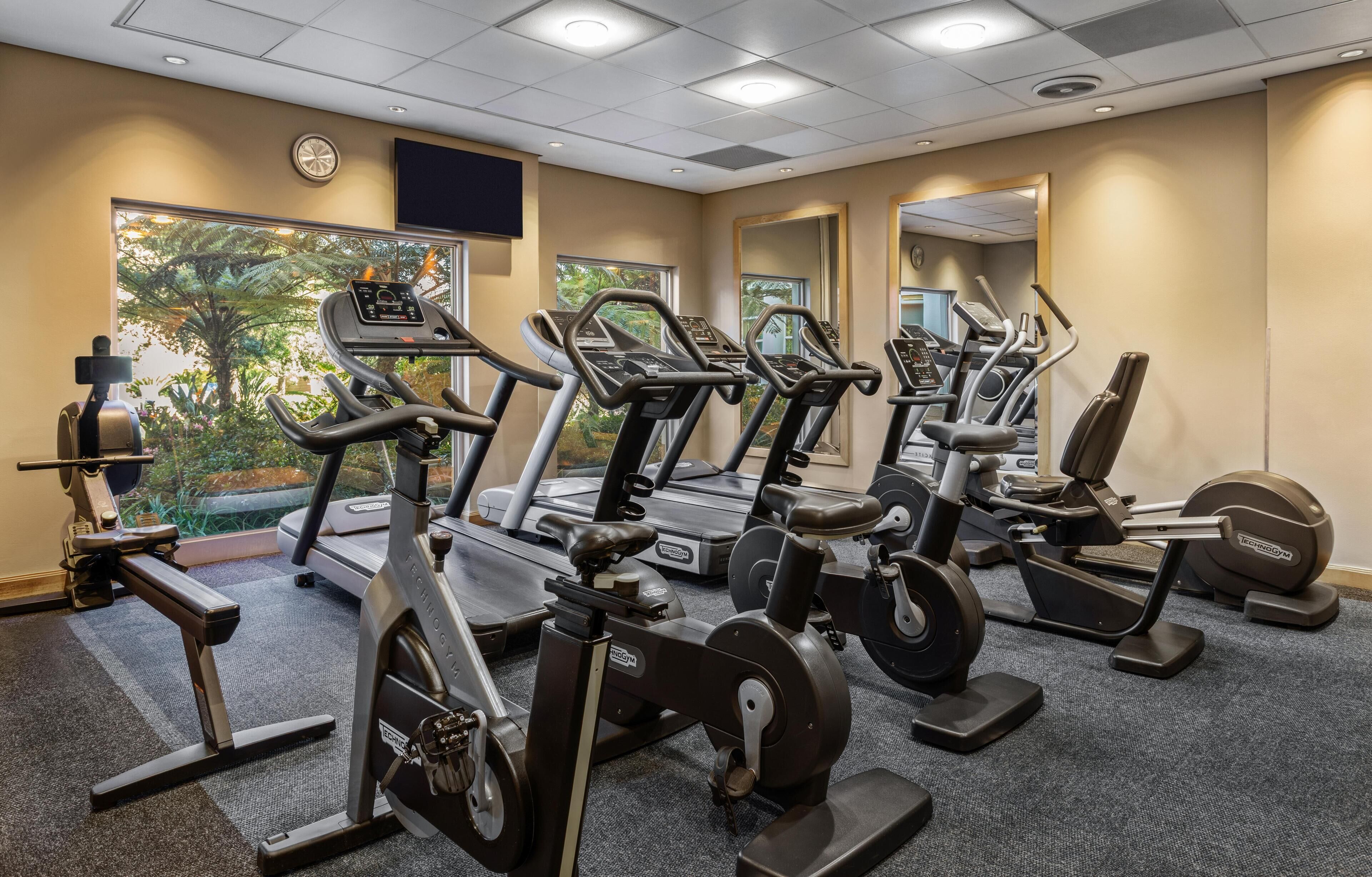 Een fitnessruimte met loopbanden, elliptische trainers en een roeimachine.