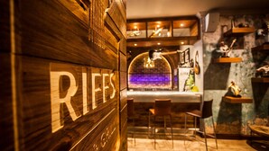 A bar area with a wooden wall displaying the word "RIFES" and a bar counter with chairs and a hanging light fixture. - Garden Court Sandton City (Sandton)