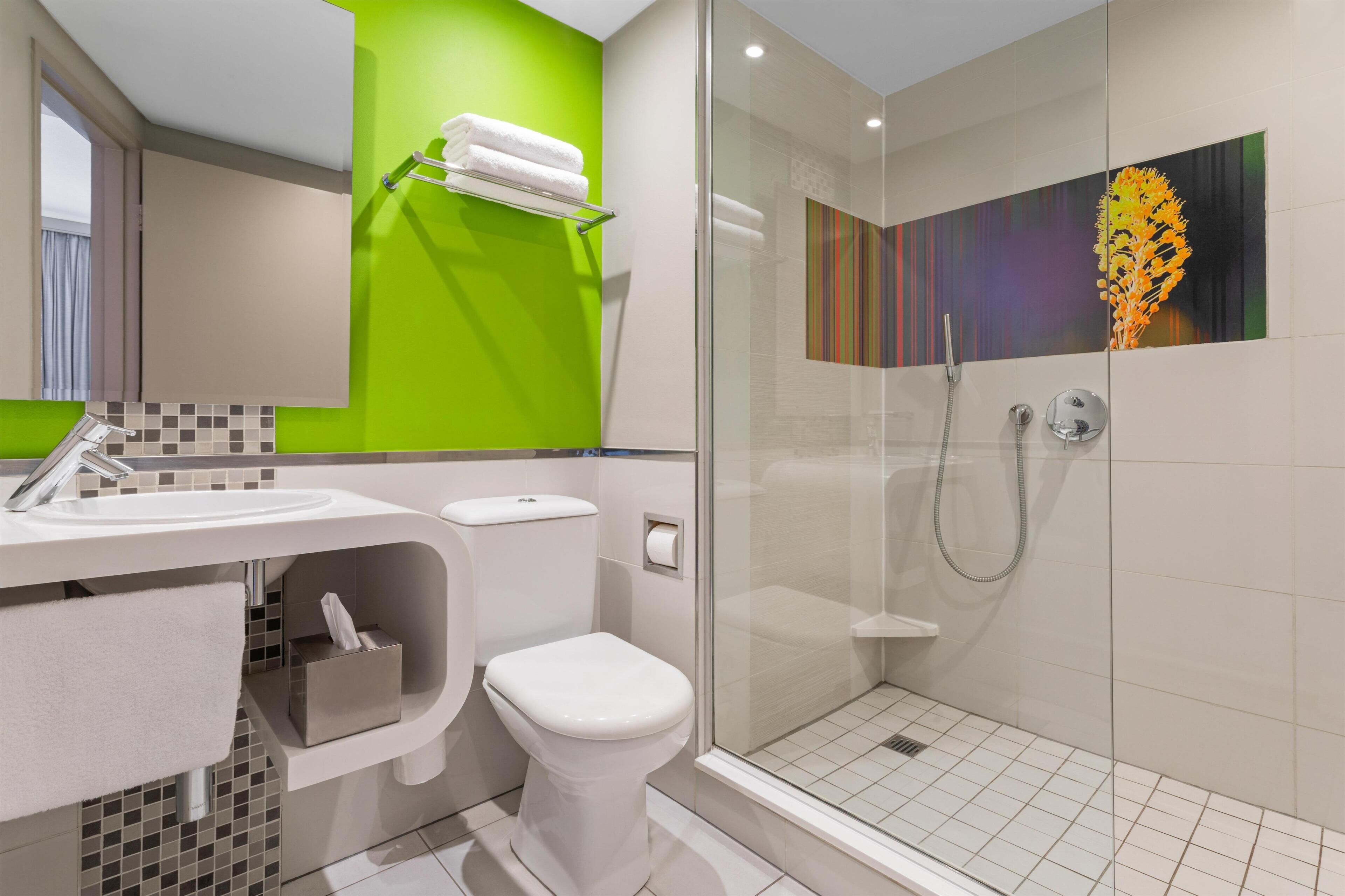 Une salle de bain moderne avec une douche à parois de verre, des toilettes blanches et un lavabo équipé d’un porte-serviettes.