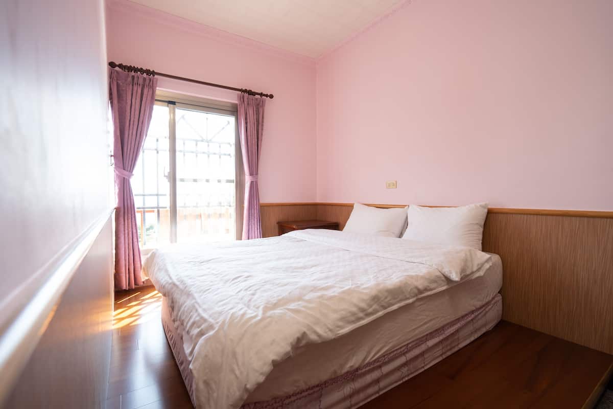 A bedroom with a large bed, wooden headboard, and pink walls.