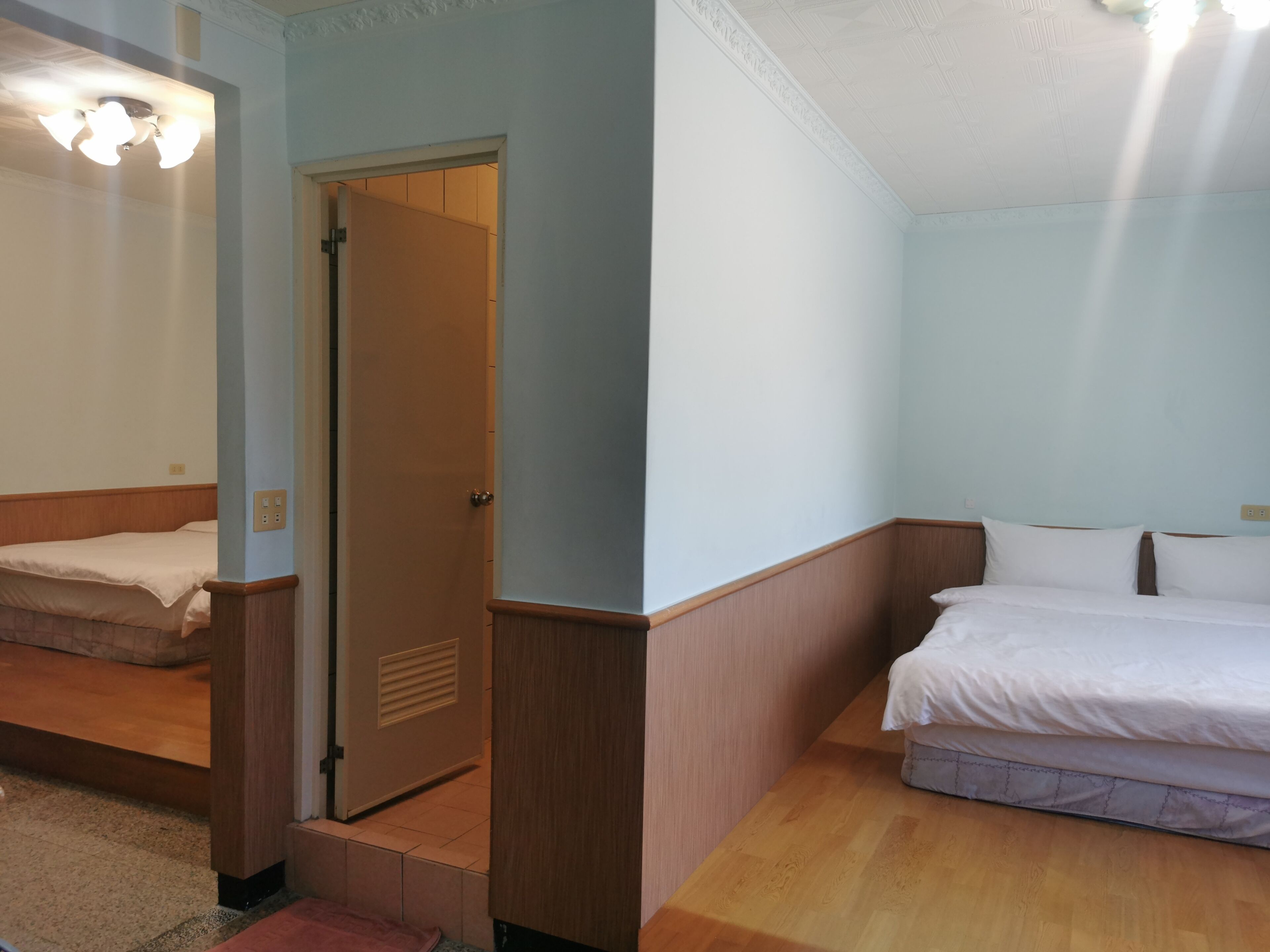 A hotel room with a bed, a desk, and a door leading to another room.