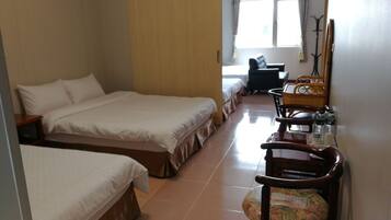 A hotel room with two single beds, a wooden nightstand, a chair, a small table with a basket, and a mirror on the wall.