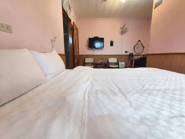 A hotel room with a large bed, two chairs, a desk, a television, and a wall-mounted fan. - Alishan Tea Homestay (Alishan)