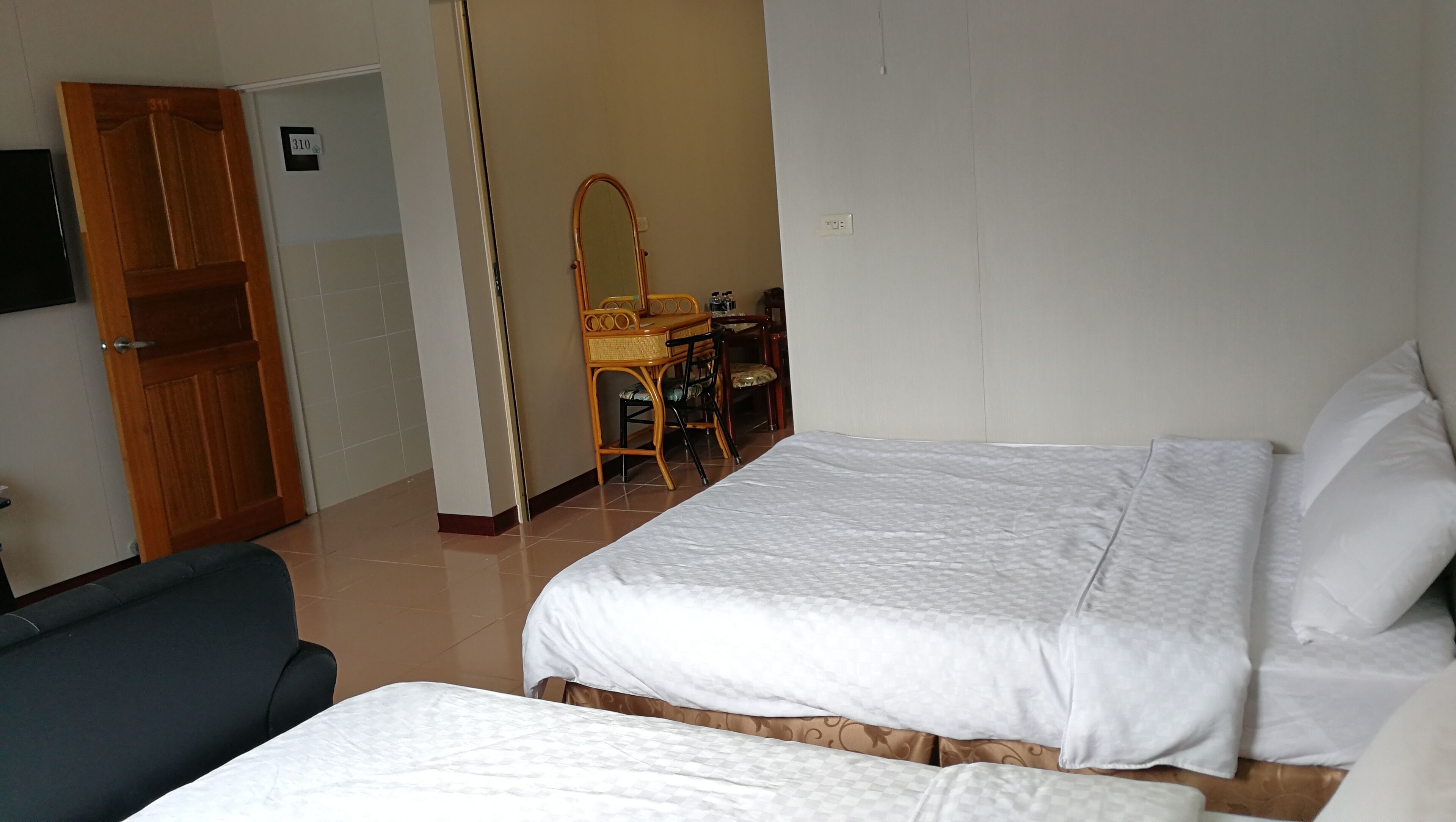 Ein Hotelzimmer mit zwei Betten, einem Schreibtisch mit Stuhl, einem Spiegel und einem Kleiderschrank.