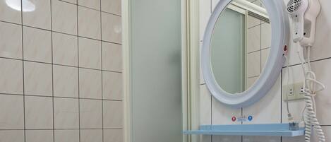 Un baño con un lavamanos blanco, un espejo y un secador de pelo sobre una estantería de pared.