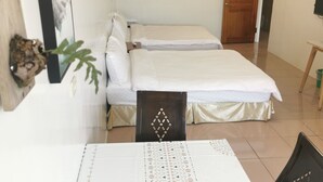 A hotel room with two beds, a dining table, chairs, a wooden door, and a wall-mounted fan. - Alishan Tea Homestay (Alishan)