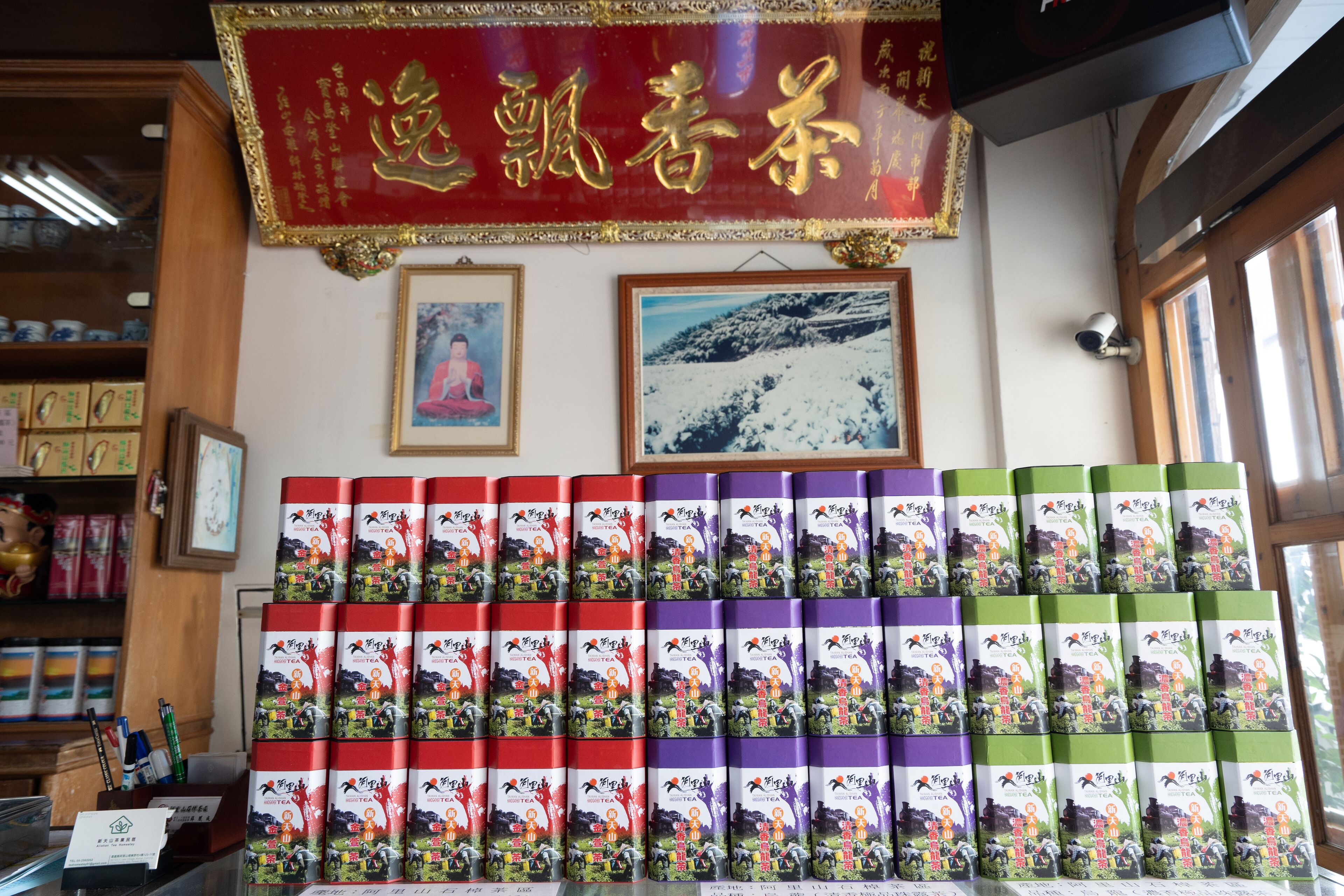 A display of tea boxes in a store with a red banner and framed pictures on the wall.