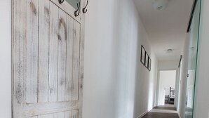 Un couloir avec une porte en bois rustique, une cloison en verre et un plancher en bois.