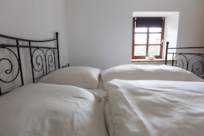 A room with two beds, a window with a view, and a white wall.