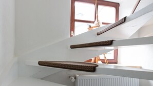 Un intérieur à plusieurs niveaux, avec un escalier, un radiateur et une fenêtre.