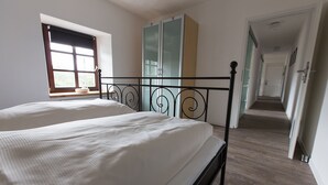 Une chambre à coucher avec un lit double, une armoire et une fenêtre avec des stores.