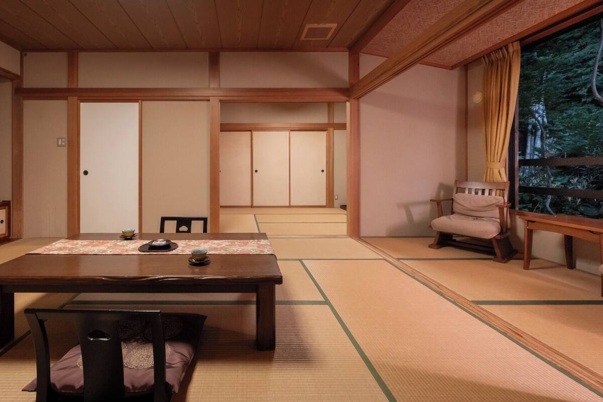 A traditional Japanese room with tatami flooring, a low table, and sliding doors.