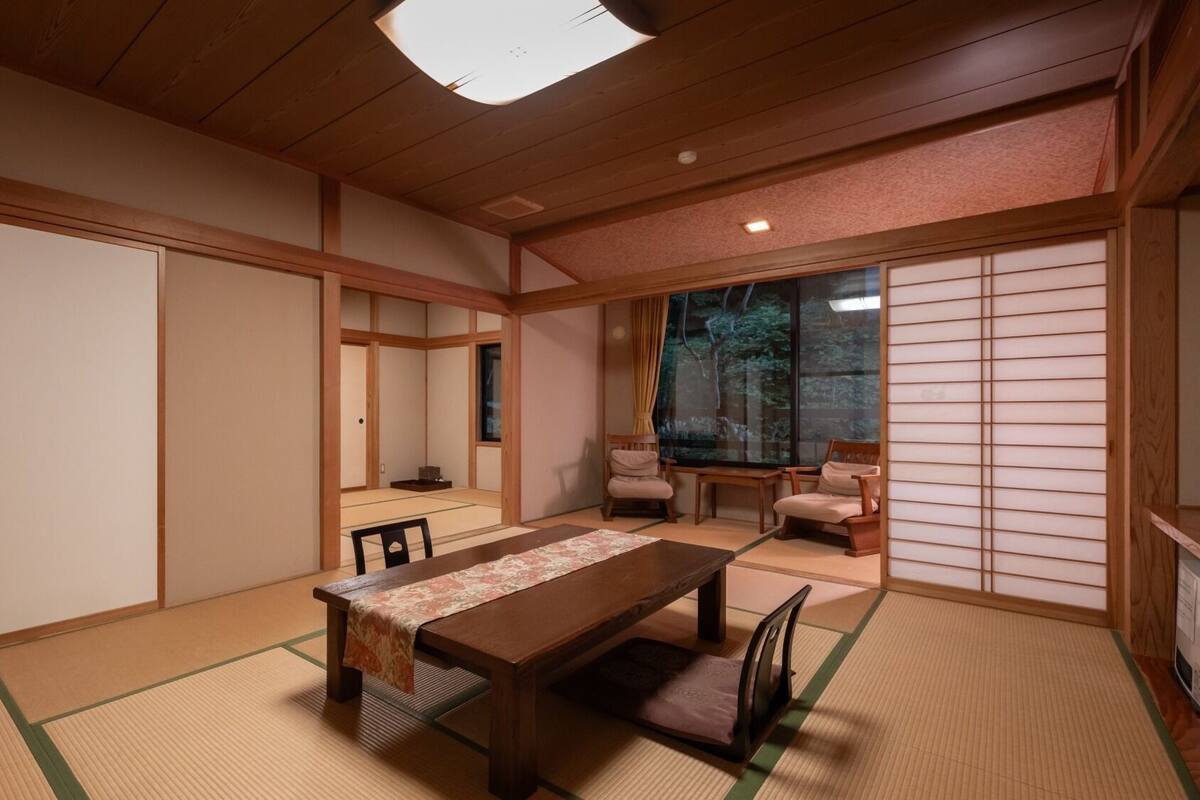 A traditional Japanese room with tatami flooring, a low table, and sliding doors.