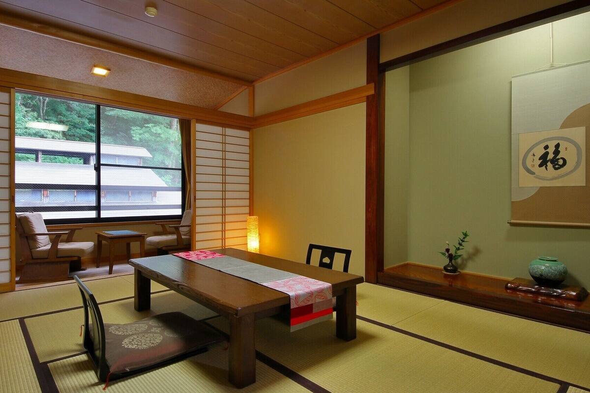 A traditional Japanese room with tatami flooring, a low table, and sliding doors.