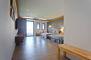 A hotel room with a wooden floor, two beds, a desk, a bench, and a large window. - Kenting Cozy B&B (Hengchun)