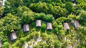 Vista aérea de un conjunto de chozas con techo de paja rodeadas de densa vegetación tropical.