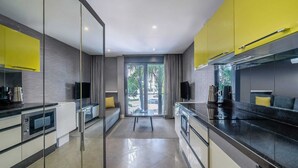 A modern kitchen with a glass partition, a dining area with a sofa, and a view through the glass doors.